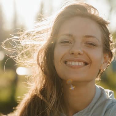A smiling woman outdoors in bright sunshine