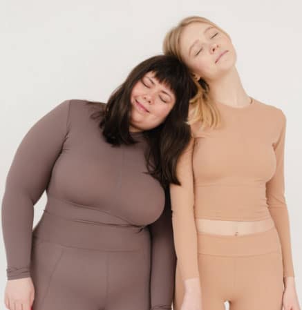 Different sized women in nude bodysuit sets rest their heads on each other