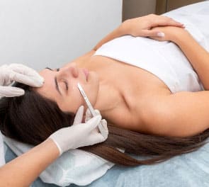 Gloved hands perform a dermaplane facial with a blade tool