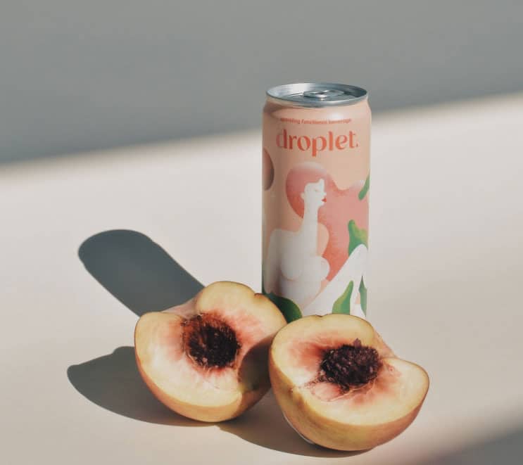 Health drink can of Droplet with modern illustrations on the label surrounded by a sliced peach