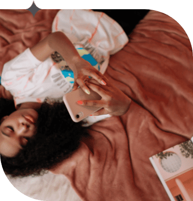 Teenage girl lies in her bed on her cellphone