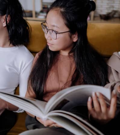 Tween girl in glasses reads a book