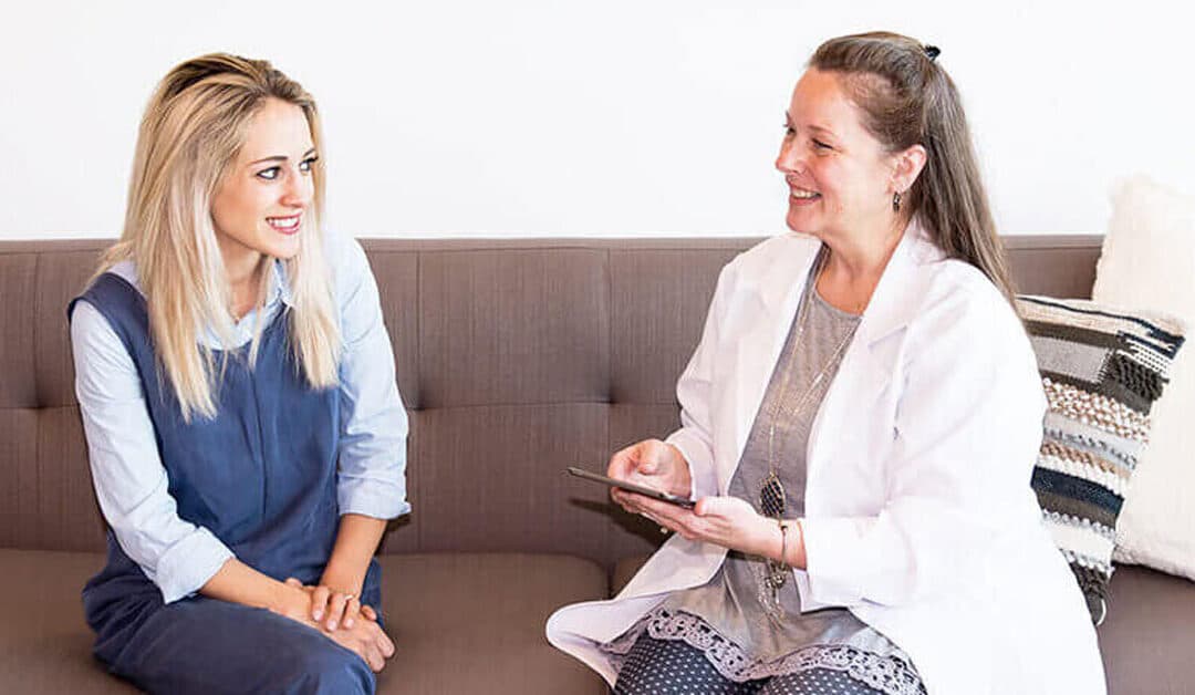 Two women sit on a couch at Aviva Woman and discuss womens health