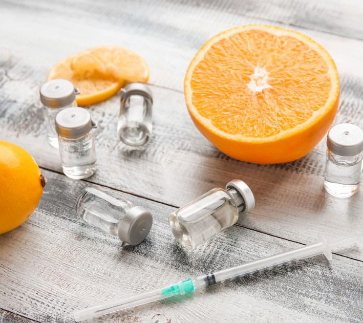 Vitamin C injections along with slices of citrus fruit on wooden background