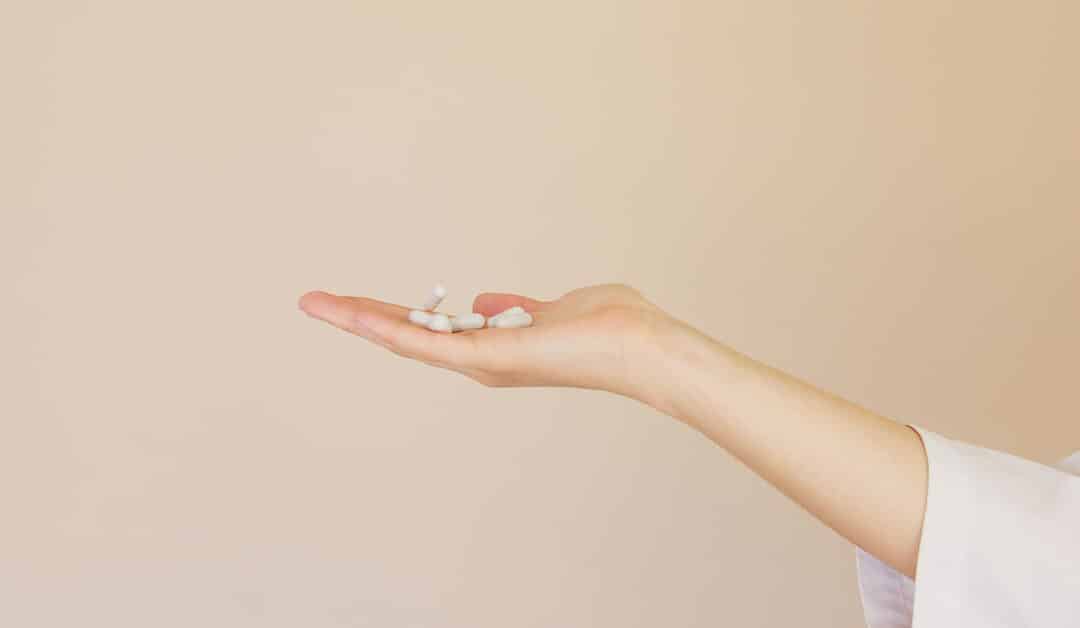 Outstretched hand on neutral background holds a handful of pills, Bioidentical Hormone Replacement Therapy