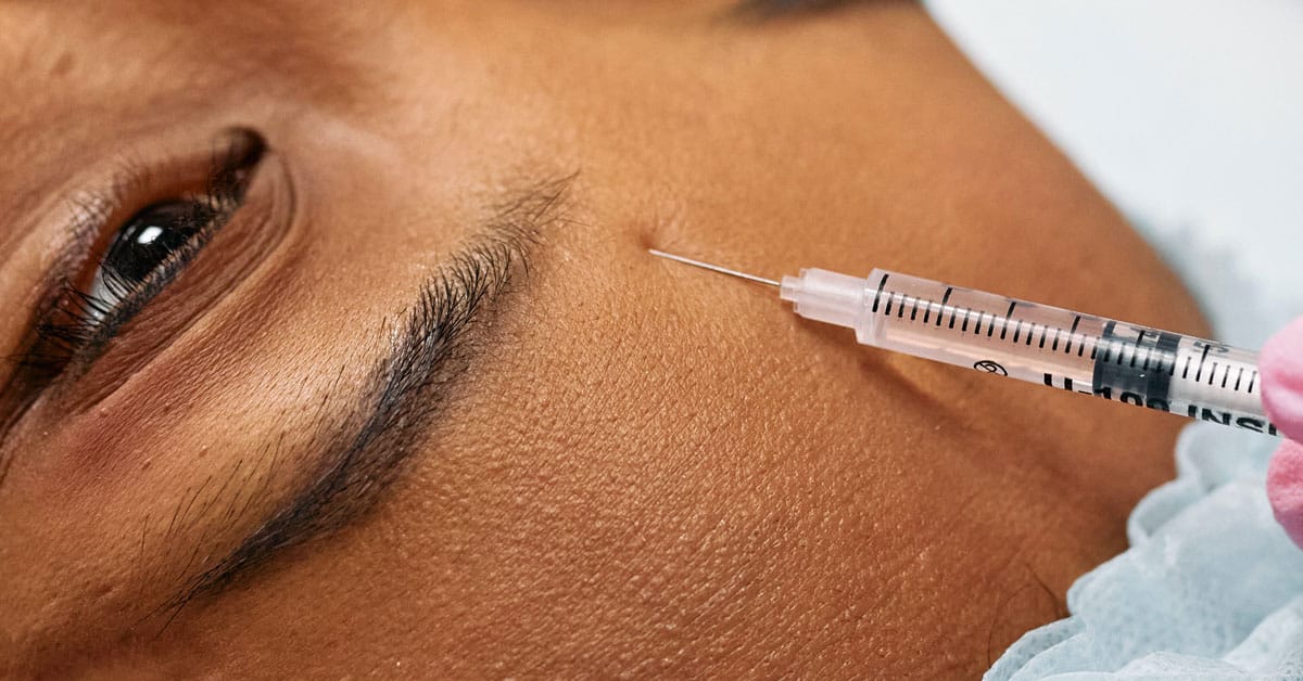 A woman's forehead gets injected with Botox