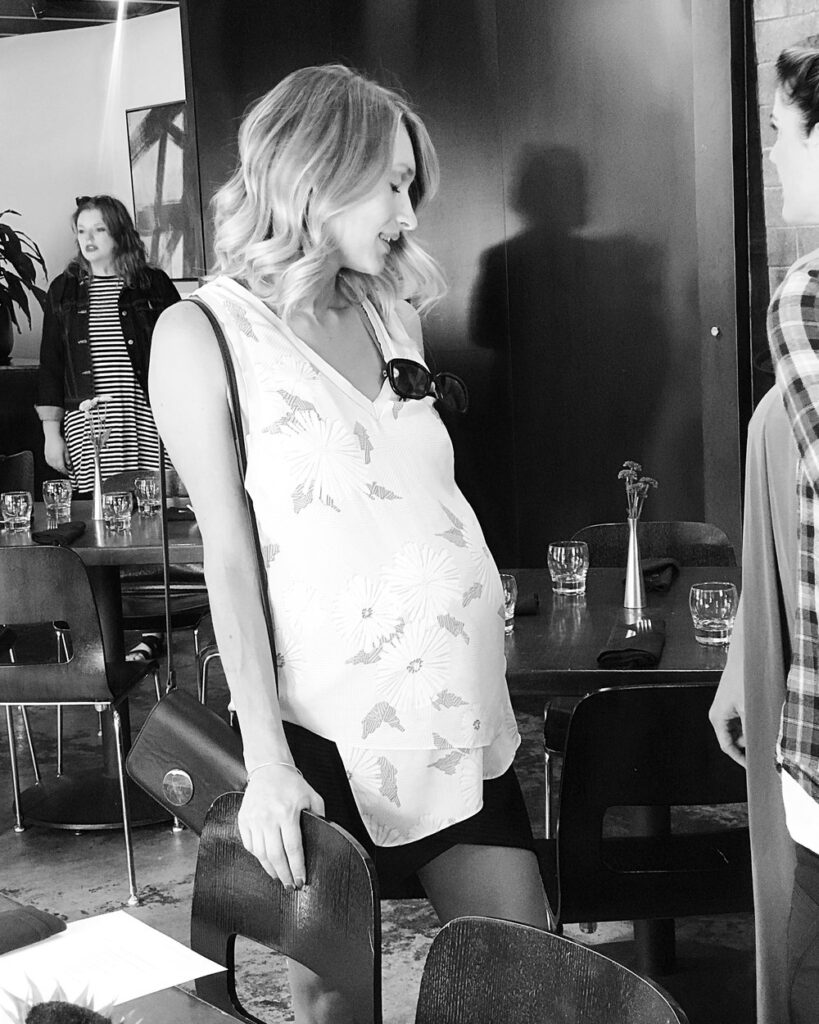 Suzi pregnant in a flowy floral top at a dining area
