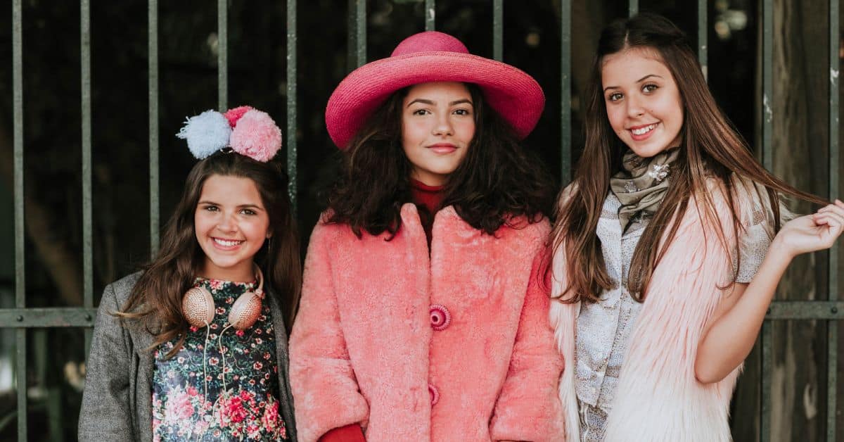 Three fashionable teen girls in pinks smile