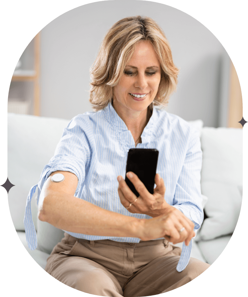 Middle aged woman holds out her arm with a continuous glucose monitor and checks the app for insights, salt lake city