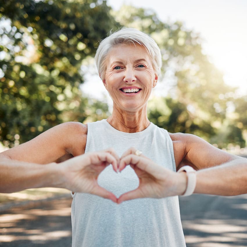 Older short-haired athletic woman holds her hands in a heart