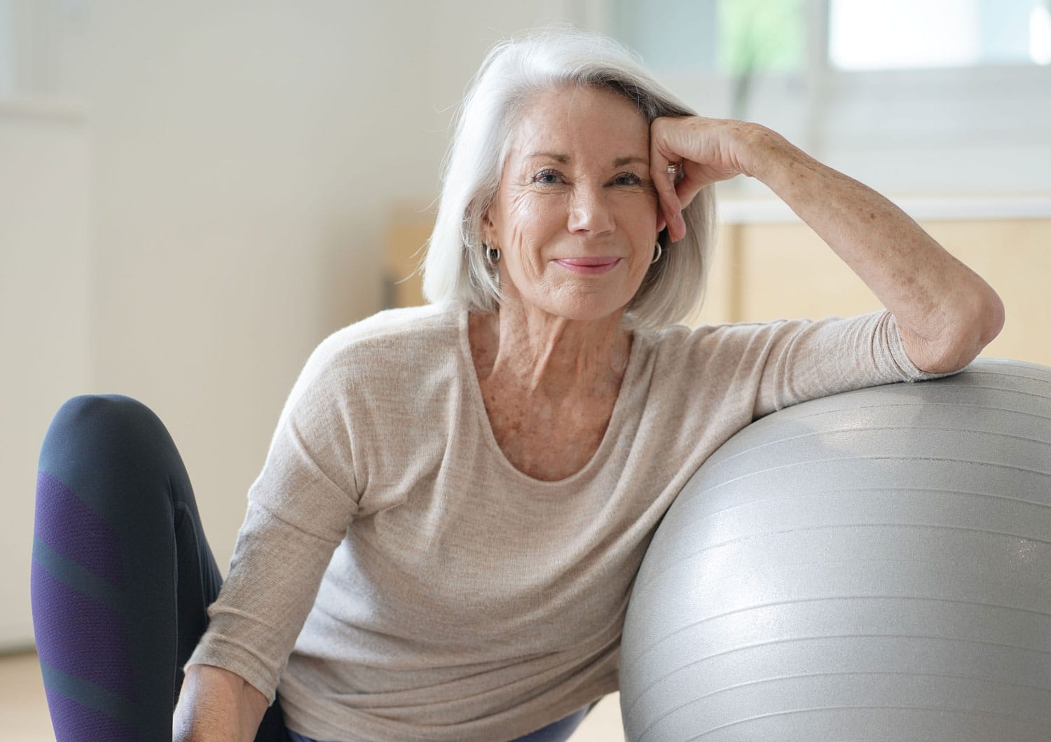 Older woman rests her head on her hand in an exercise studio, vaginal labial wing lift in salt lake city.jpg